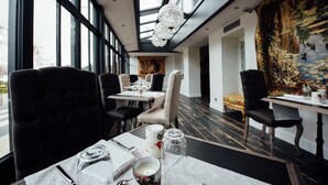 Een restaurant met een modern interieur, met zwarte beklede stoelen, witte tafels en een groot raam met uitzicht op de straat.
