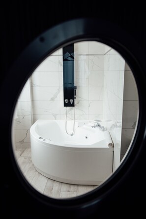 A modern bathroom with a large, round bathtub, a handheld showerhead, and marble walls. - Amirauté (La Baule-Escoublac)