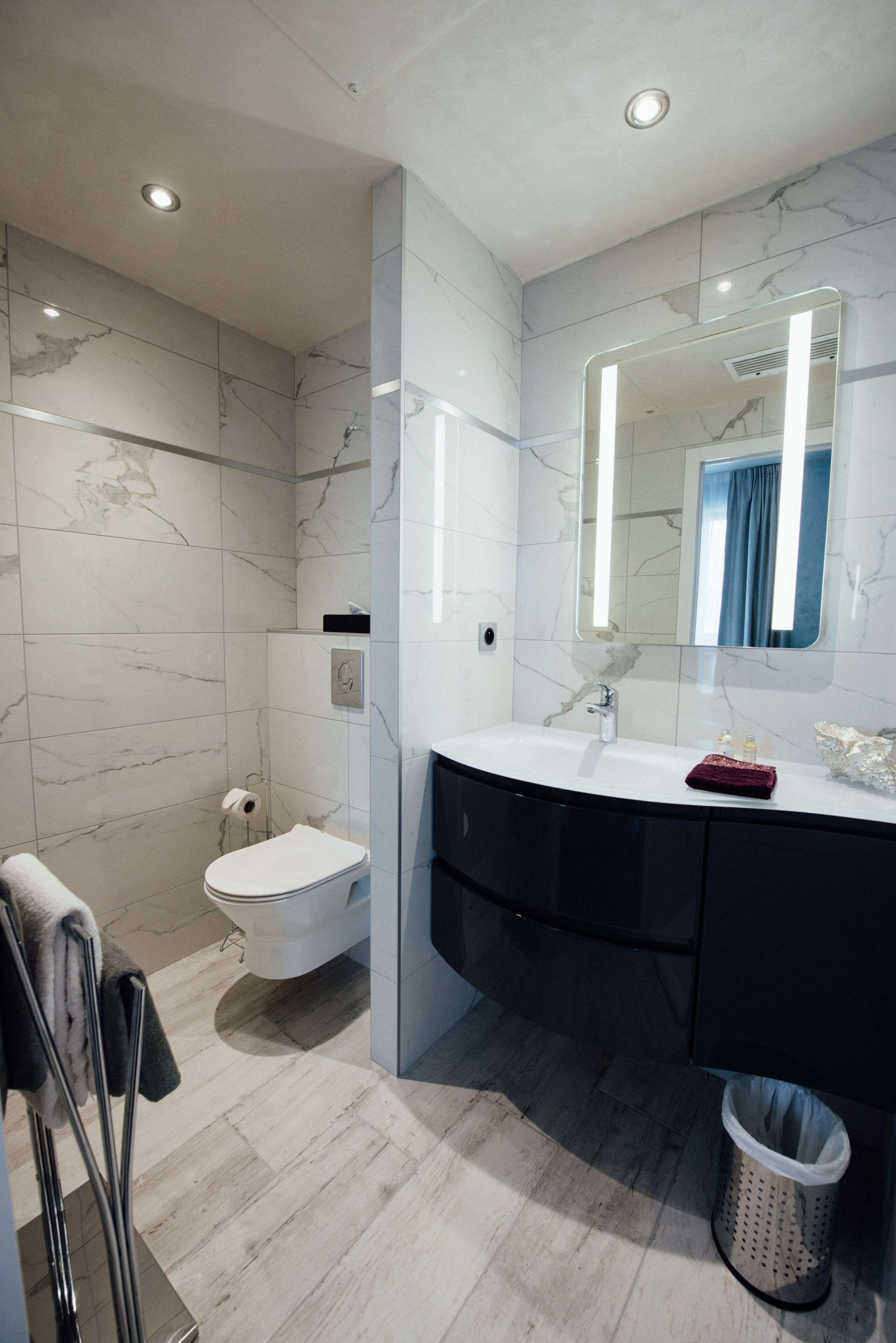 A modern bathroom with a white toilet, a sink with a mirror, and a shower area.