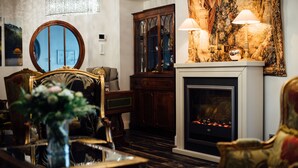 Een klassieke woonkamer met een open haard, versierde meubels en een grote spiegel.