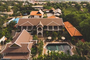 A large building with multiple roofs, a swimming pool, and surrounding greenery. - ChampeySor Angkor Boutique Hotel (Siem Reap)