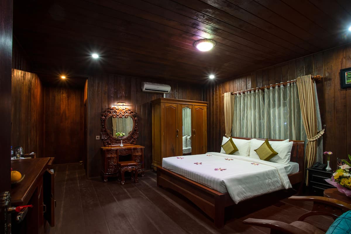 Un dormitorio con paneles de madera, una cama, un tocador y un espejo.