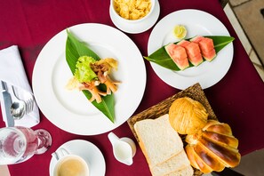A table set with plates of food, including watermelon and bread, and a basket of chips. - ChampeySor Angkor Boutique Hotel (Siem Reap)