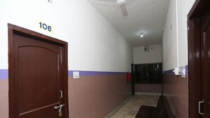 A hallway with a brown door labeled "106", a ceiling fan, and a red fire extinguisher. - Chilika Residency (Bhubaneshwar)