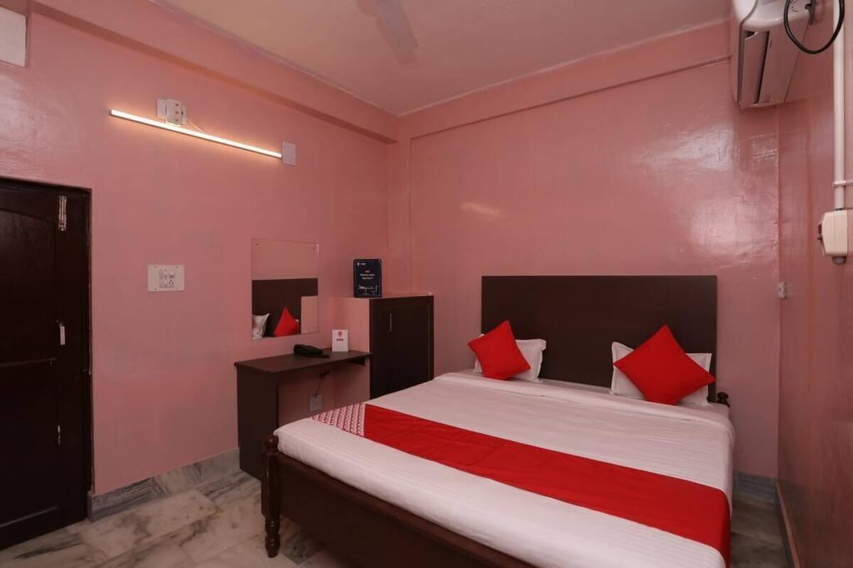 A bedroom with a bed, a desk, a mirror, and a wall-mounted air conditioning unit.