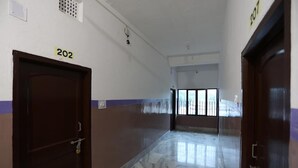 A hallway with doors numbered 202 and 207, marble flooring, and a window at the end. - Chilika Residency (Bhubaneshwar)