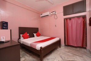 A bedroom with a bed, a desk, an air conditioning unit, and a wardrobe. - Chilika Residency (Bhubaneshwar)