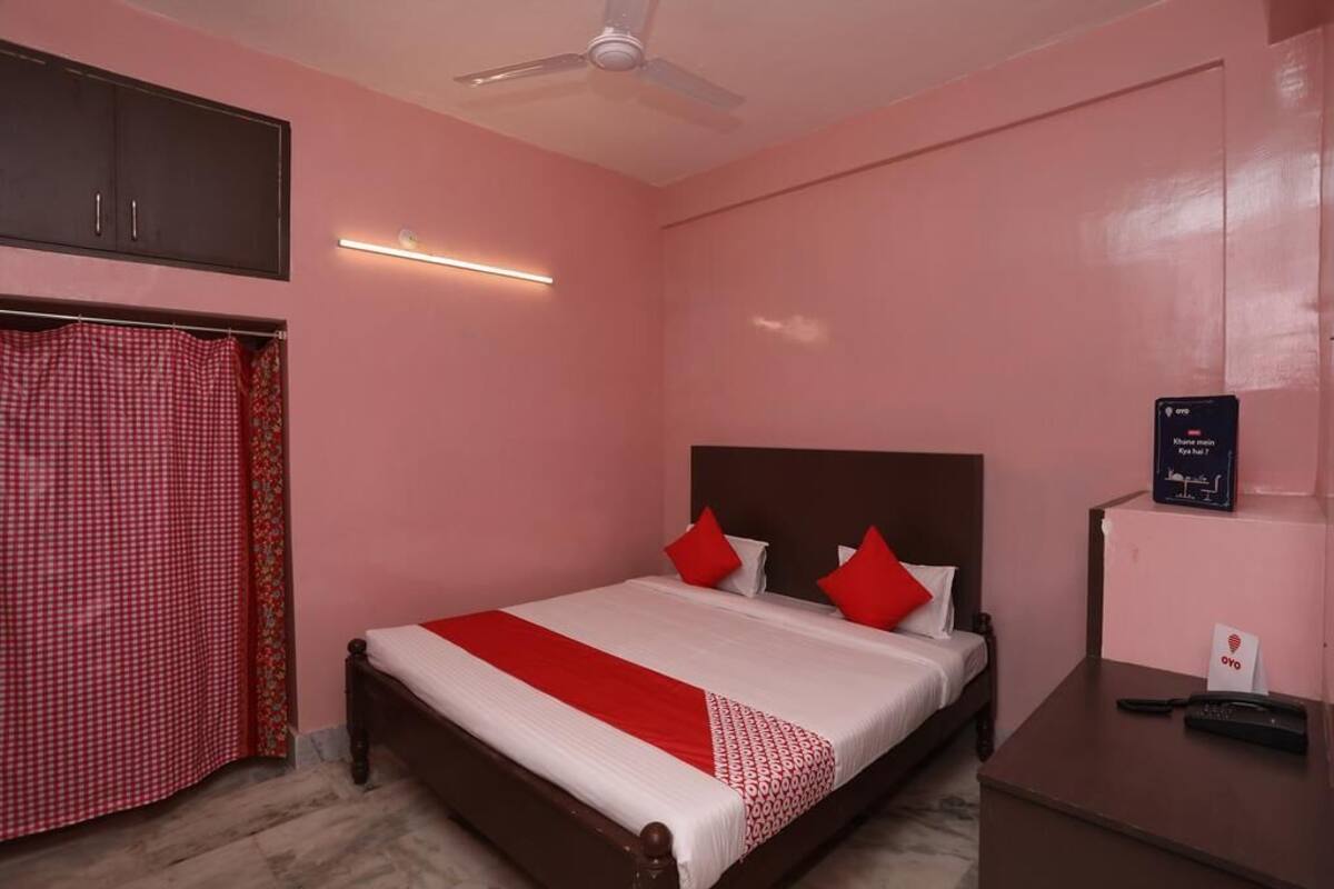 A bedroom with a bed, a ceiling fan, a bedside table with a remote control, and a wall-mounted sign.