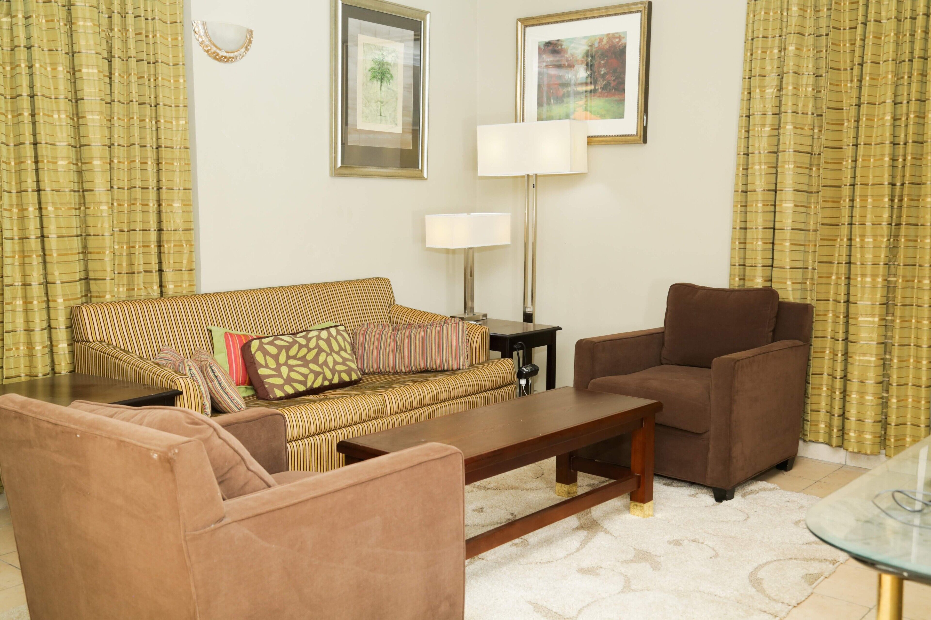 A living room with a striped sofa, a brown armchair, a coffee table, and a lamp.