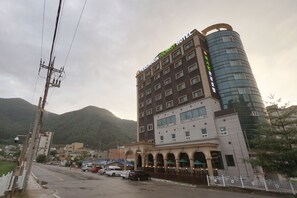L’hôtel Persimmon Tourist, doté d’un design moderne, se distingue par sa façade en verre incurvé et ses nombreux balcons.