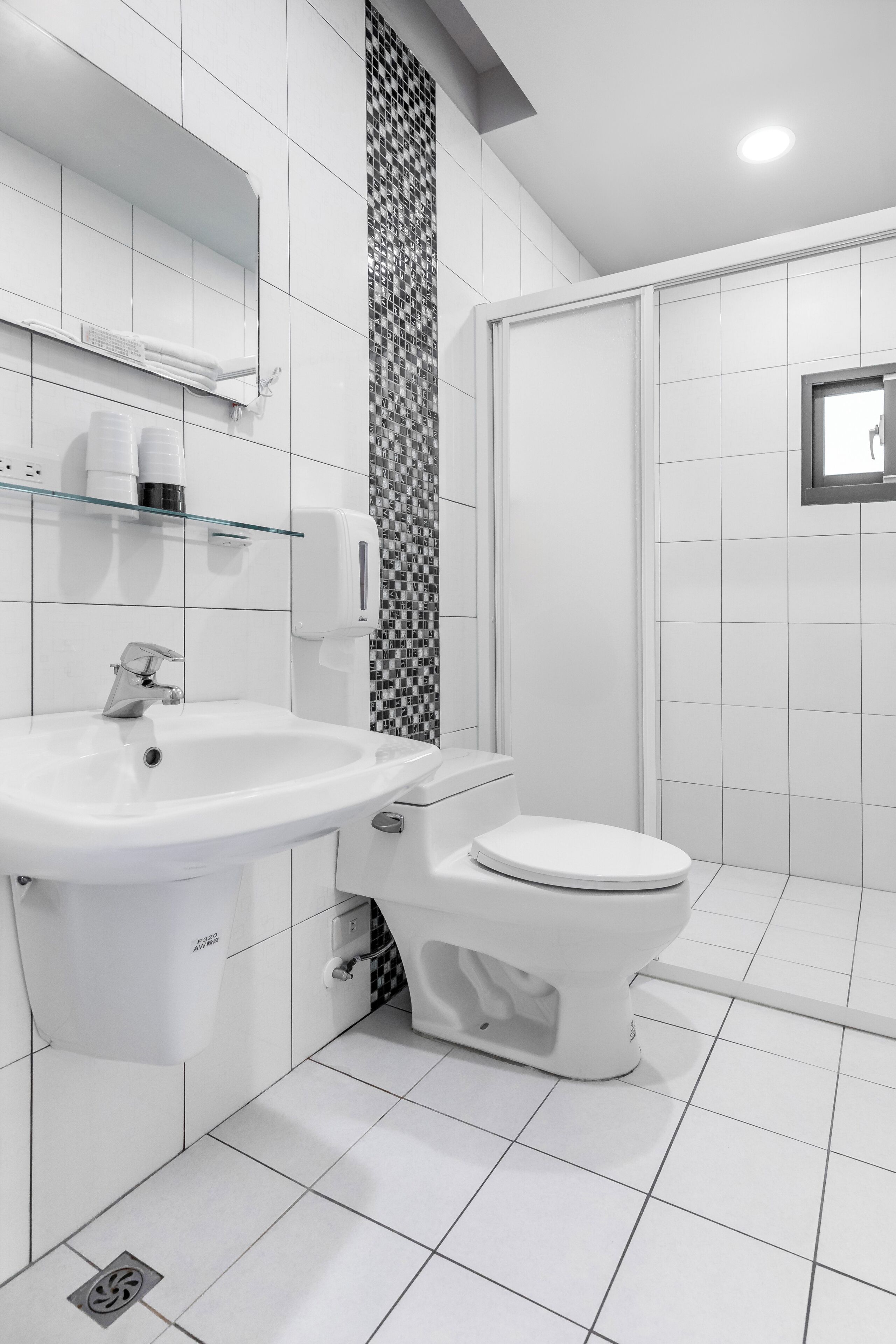 A modern bathroom with a white sink, toilet, and shower.