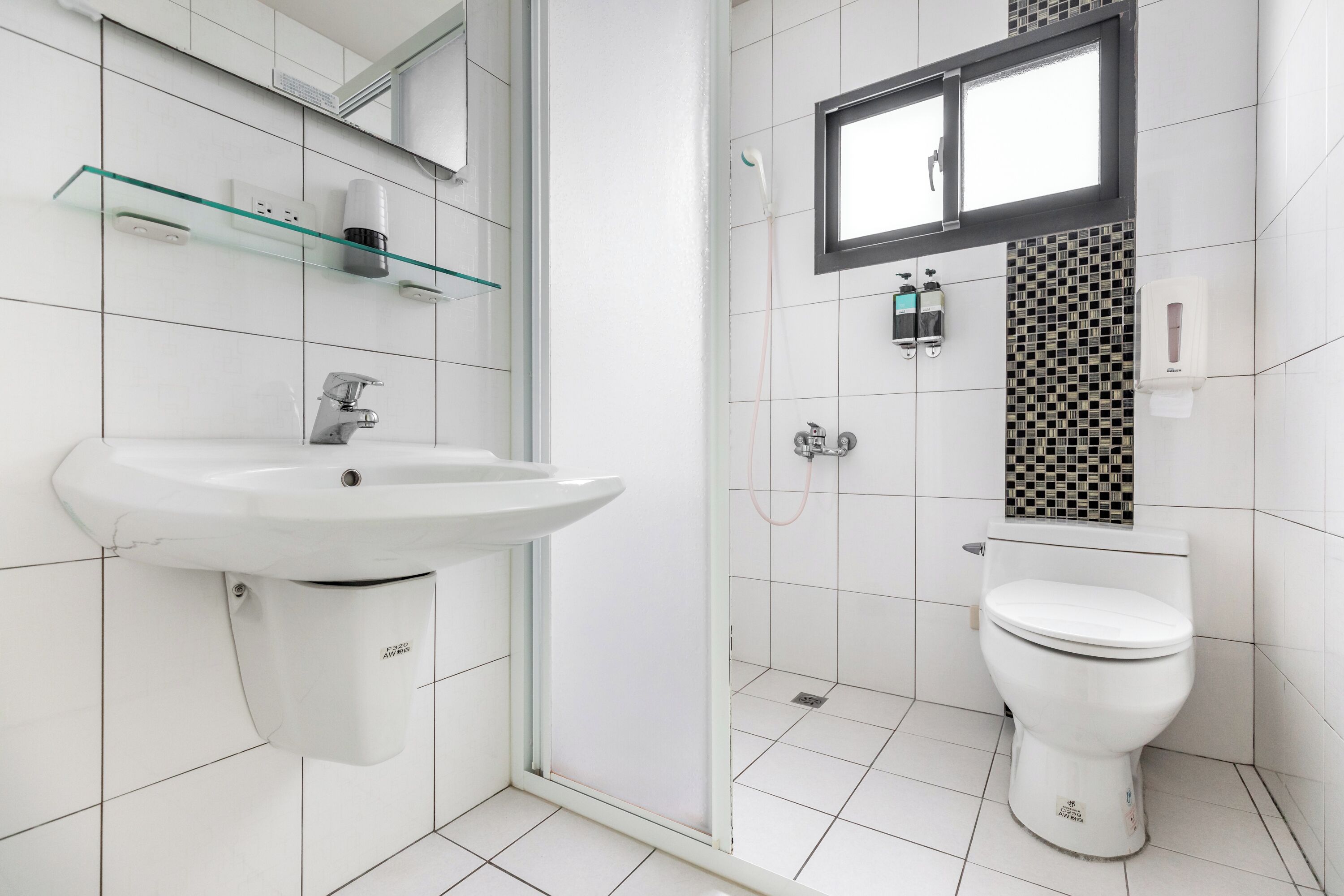 Une salle de bain moderne avec un lavabo blanc, des toilettes et une douche séparée par une paroi en verre.
