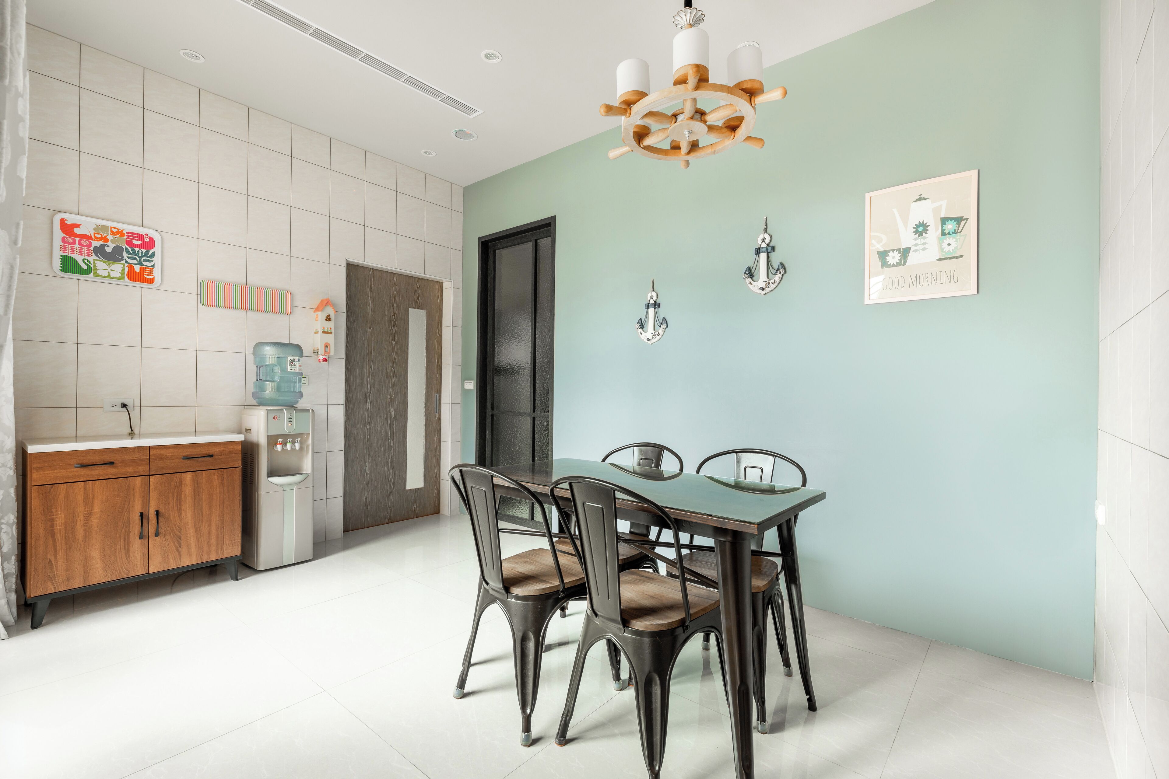 Un comedor con una mesa y sillas, un dispensador de agua y un refrigerador.