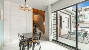 A modern dining area with a glass door leading to an outdoor patio. - Summer Crazy (Magong)