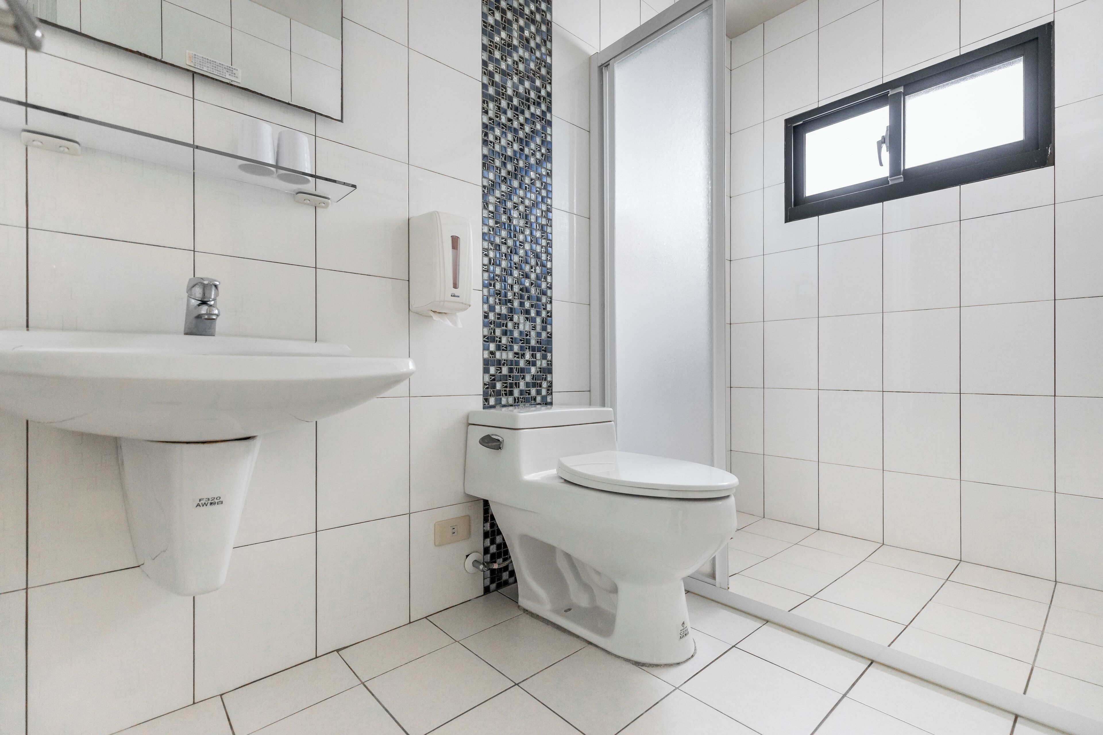 A bathroom with a white sink, toilet, and shower area.