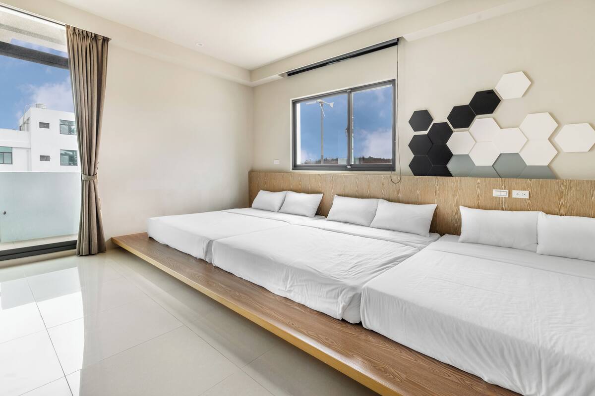Ein modernes Hotelzimmer mit großem Fenster, Holz-Kopfteil und einer geometrischen Wanddekoration.