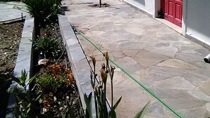 Un cortile con pavimento in pietra, porte rosse e piante in vaso.