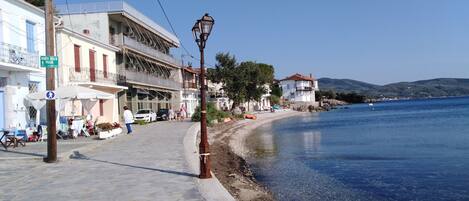 A coastal street with buildings, a clear sky, and a calm sea.