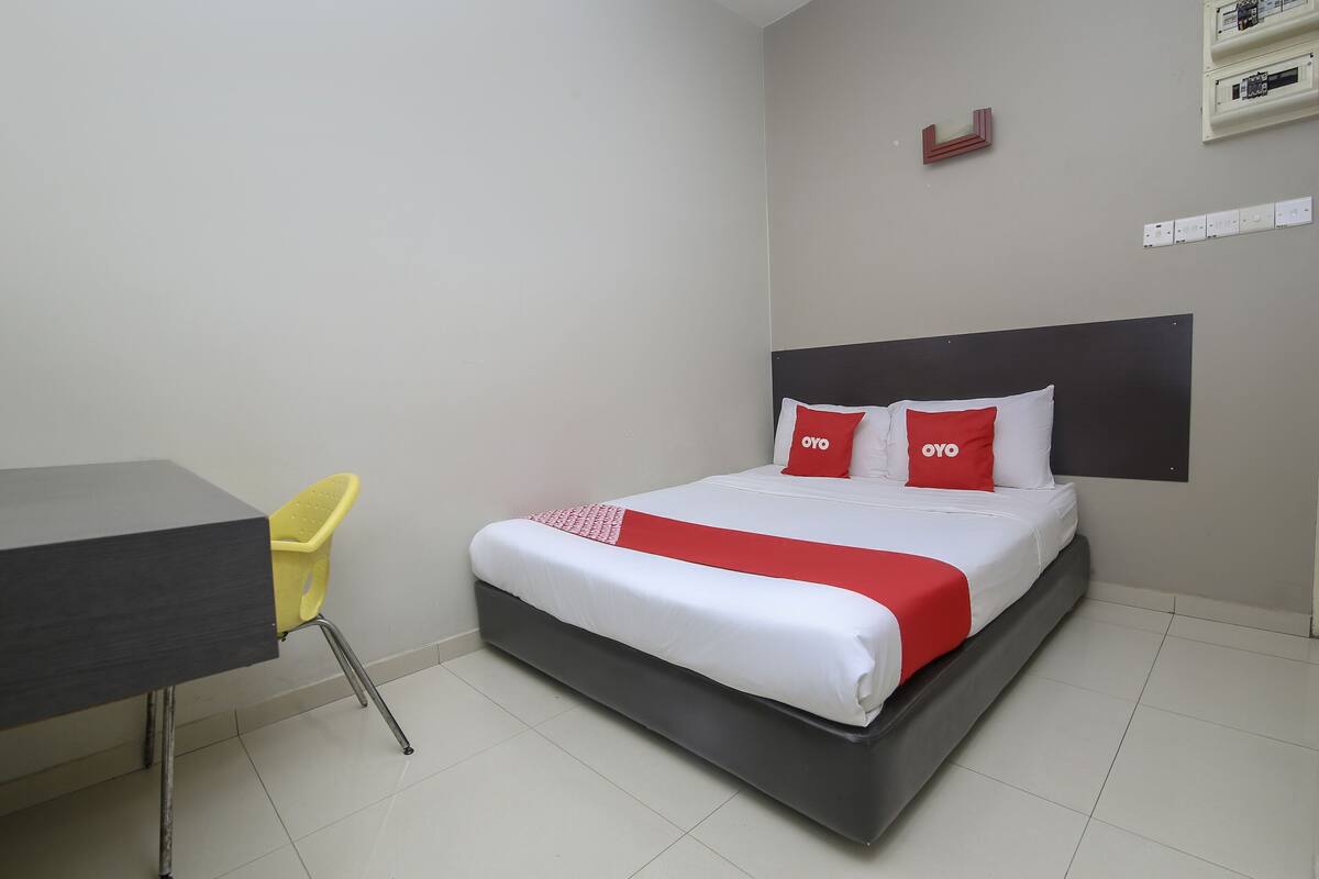 A hotel room with a bed, a desk, and a chair.