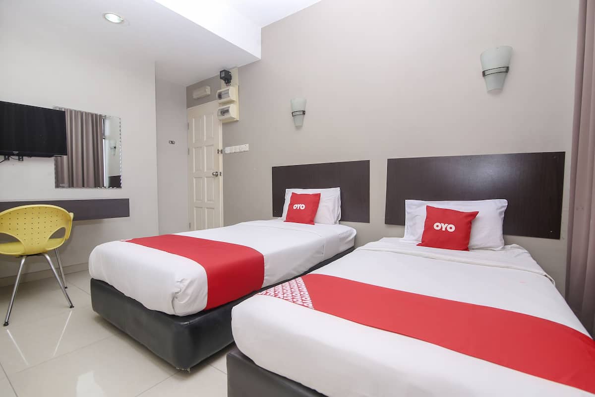 Two beds with red and white bedding, a yellow chair, and a ceiling light.