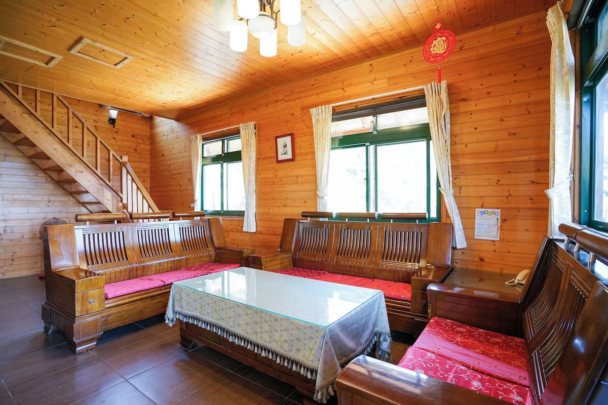 Interior de una cabaña de madera con un sofá, una mesa y una escalera.