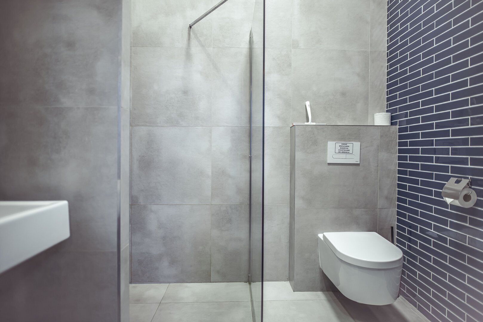 Un baño moderno con ducha, inodoro y pared con azulejos.