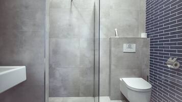 Un baño moderno con ducha, inodoro y pared con azulejos.