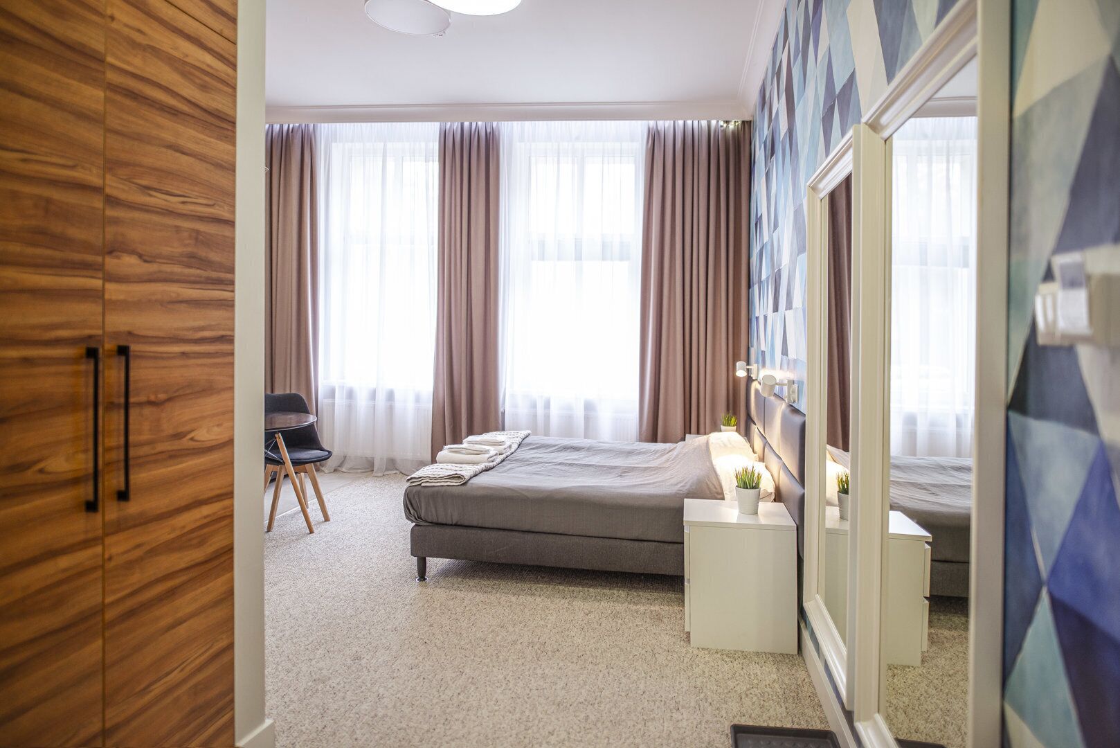 A hotel room with a bed, a chair, a nightstand, and a wardrobe.