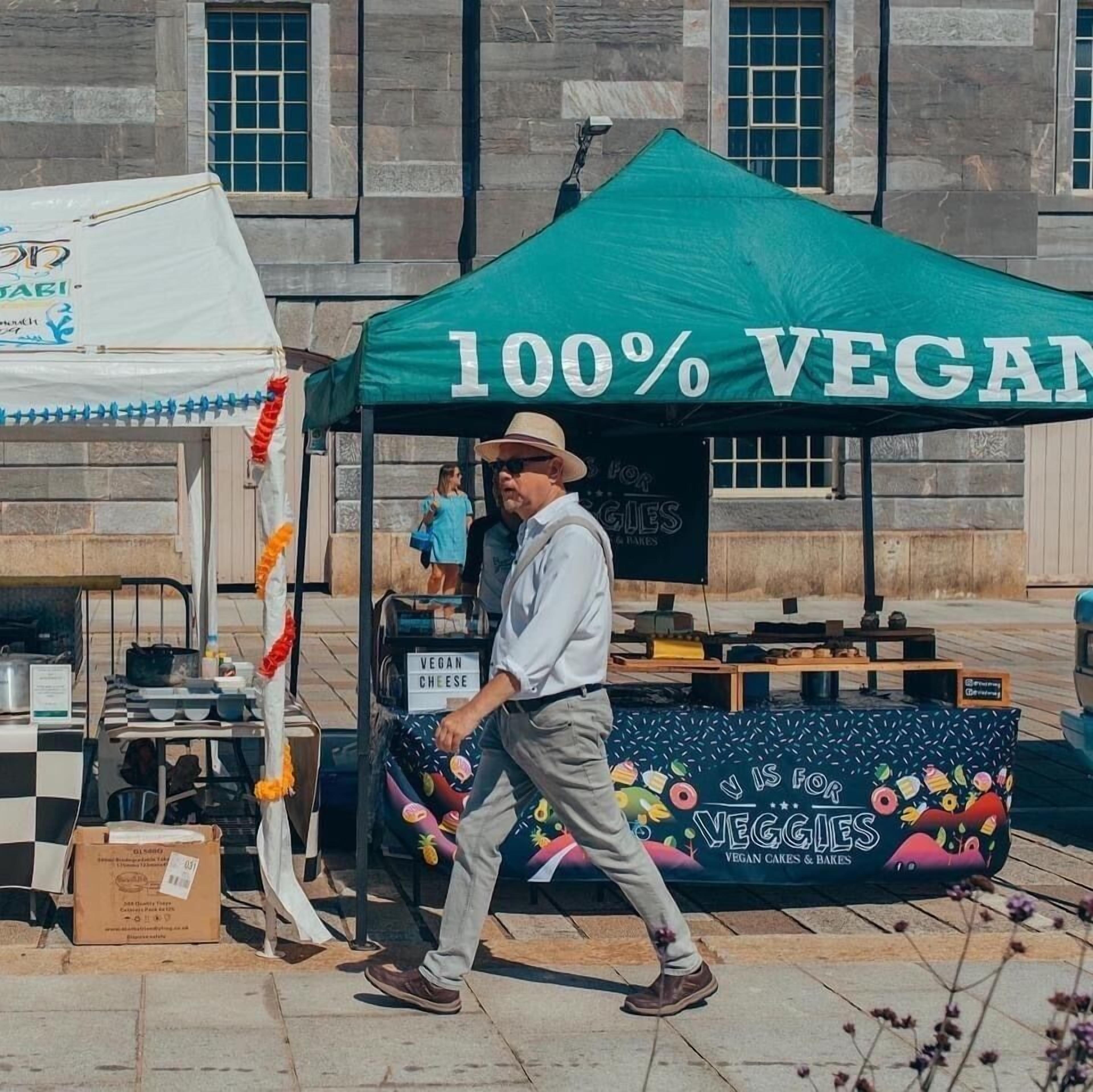 A street food vendor with a green tent advertising 100% vegan options.