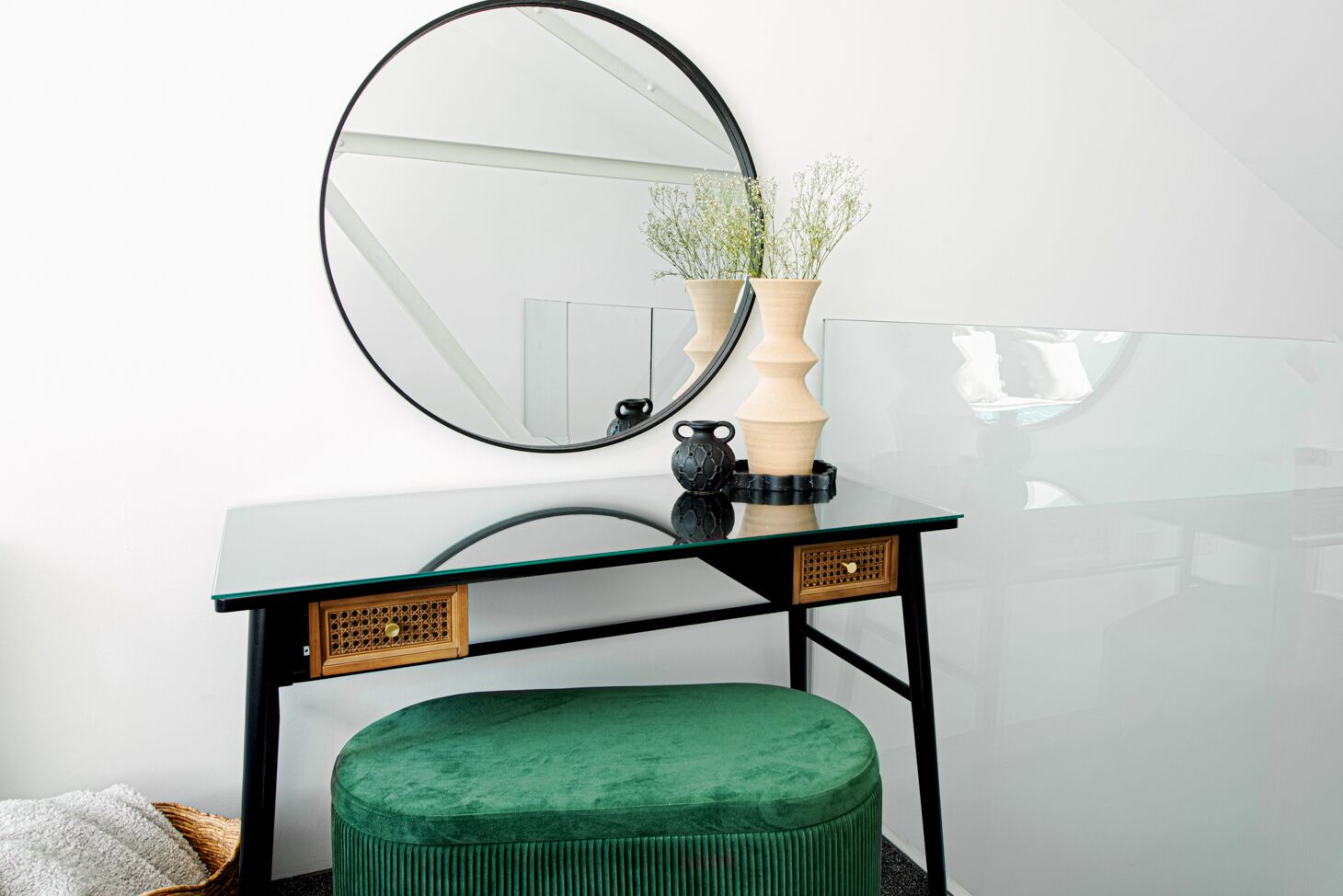 Un moderno lavabo con piano in vetro, uno specchio rotondo e un poggiapiedi verde.