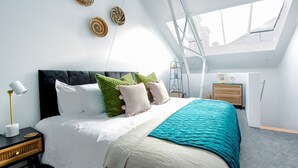 A modern bedroom with a large bed, a skylight, and a view of the city. - RWY Suite48 (Plymouth)