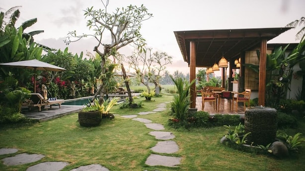 A garden pathway leading to a wooden structure with outdoor seating. - The Runik Ubud (Ubud)