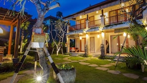 A two-story building with a balcony, a well-lit entrance, and a garden with a stone pathway. - The Runik Ubud (Ubud)
