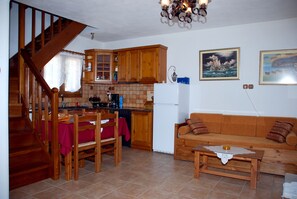Una cocina con armarios de madera, una mesa de comedor con sillas, un sofá y una escalera.