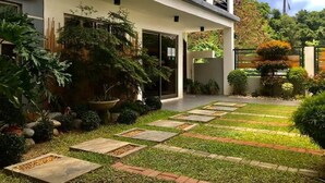 A modern house with a well-maintained garden, a stone pathway, and a balcony. - Rold and Roub Home Suites by Cocotel (Puerto Galera)