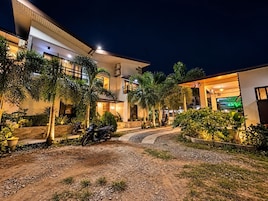 A modern building with a well-lit entrance, a paved driveway, and several motorcycles parked outside.