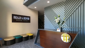 A reception area with a sign reading "ROLD & HOME SUITES" and a modern reception desk with a logo. - Rold and Roub Home Suites by Cocotel (Puerto Galera)