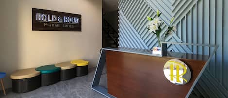 Un espace d’accueil avec une enseigne indiquant « ROLD & HOME SUITES » et un comptoir d’accueil moderne orné d’un logo.