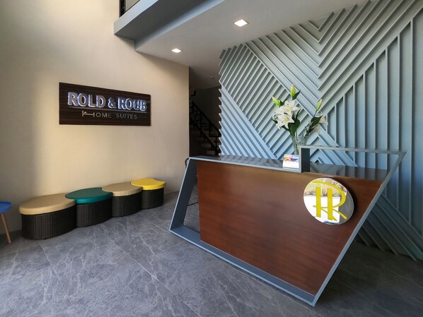 A reception area with a sign reading "ROLD & HOME SUITES" and a modern reception desk with a logo.