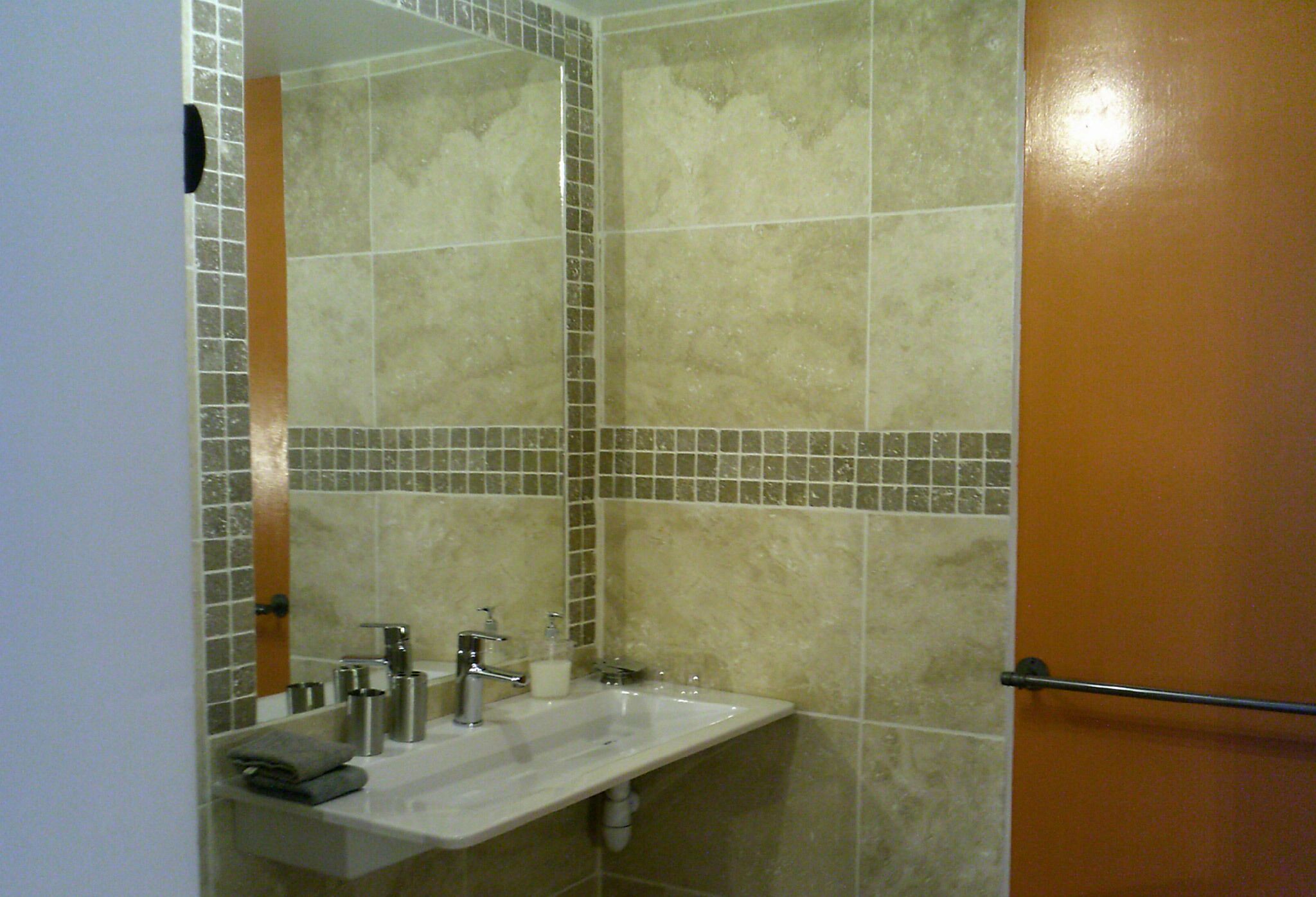 Une salle de bain avec un lavabo, un miroir et des murs carrelés.