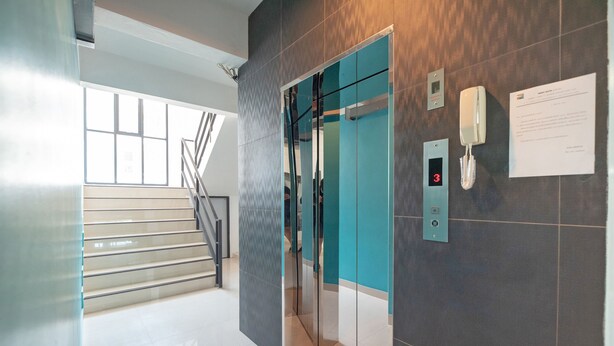 A modern elevator with a digital display, a phone, and a notice on the wall.