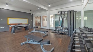 A modern gym with exercise equipment, a whiteboard, and a wooden table.