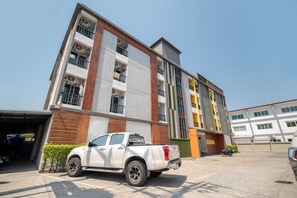Un edificio de varios pisos con fachada blanca y acceso a un garaje.