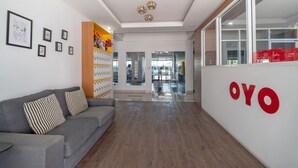 A modern reception area with a grey sofa, framed pictures on the wall, and a large 'OYO' sign.