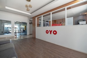 Un área de recepción con un mostrador de madera, una partición de vidrio y un letrero que dice "OYO".