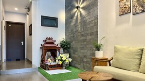 A modern living room with a wooden shrine, a sofa, and a small table.