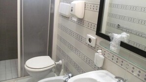 A bathroom with a toilet, a sink, a glass shower enclosure, and a mirror.