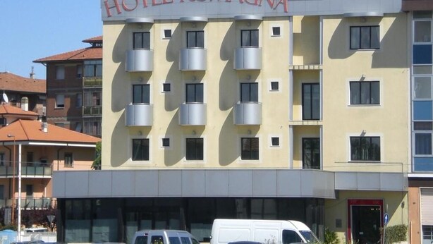 A hotel named "HOTEL ROMAGNA" with a modern facade, multiple balconies, and a clear sky.