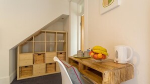 Una habitación acogedora con un escritorio de madera, una silla, un frutero y una cafetera.