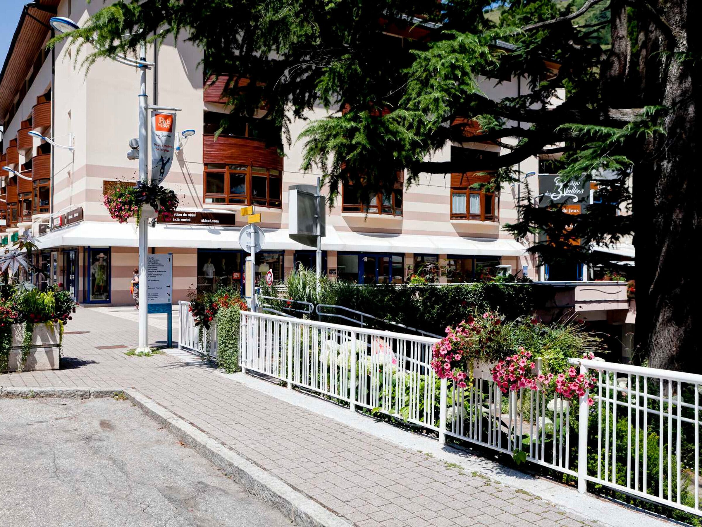Ein Hotel mit weißer Fassade, Balkonen und Blumenkästen.